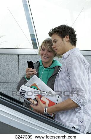 Teenager couple using mobile phone on escalator, side view View Large Photo Image Stock Photo - Teenager couple using mobile phone on escalator, side view . Fotosearch