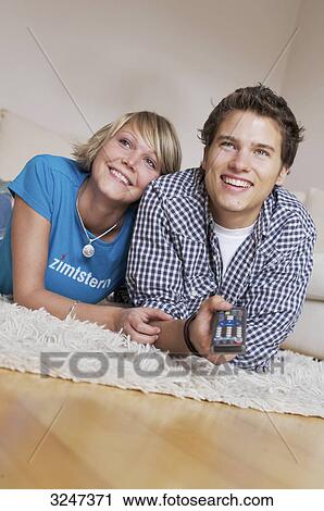 Teenager lying on carpet and watching television, slanted view View Large Photo Image Stock Image - Teenager lying on carpet and watching television, slanted view . Fotosearch