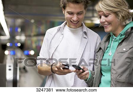 Teenagers changing phone numbers at train station, waist up View Large Photo Image Stock Image - Teenagers changing phone numbers at train station, waist up . Fotosearch