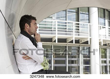Thoughtful businessman standing in archway, side view View Large Photo Image Stock Photo - Thoughtful businessman standing in archway, side view . Fotosearch