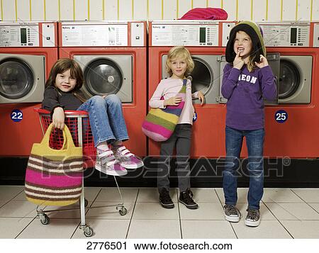 Stock Image - Three children in front of washing machines . Fotosearch