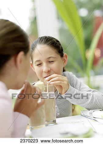 Stock Image - Two girls drinking chocolate milk with straw . Fotosearch