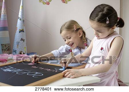 Two girls writing on chalkboard View Large Photo Image Stock Image - Two girls writing on chalkboard . Fotosearch