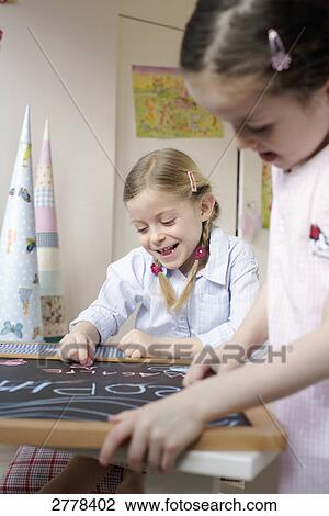 Stock Image - Two girls writing on chalkboard . Fotosearch