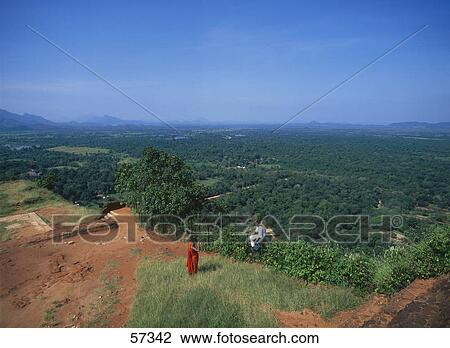 Stock Image - Two people on a hilltop over looking a valley, Sigiriya, Sri Lanka . Fotosearch