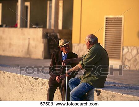 Two senior men sitting on wall and talking, Slovenia View Large Photo Image Stock Photo - Two senior men sitting on wall and talking, Slovenia . Fotosearch