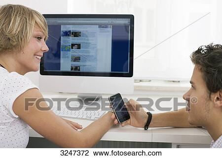 Two teenager changing phone numbers in internet cafe, side view View Large Photo Image Stock Image - Two teenager changing phone numbers in internet cafe, side view . Fotosearch