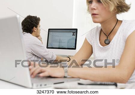 Stock Image - Two teenager using laptop and desktop computer, horizontal format . Fotosearch