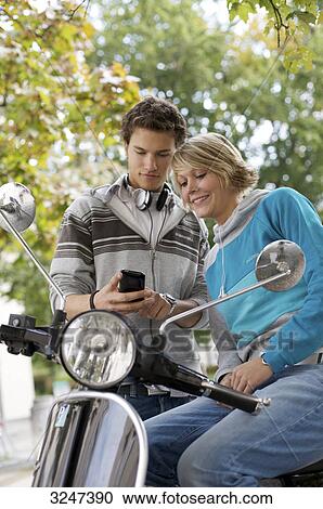 Stock Image - Two Teenager with autocycle using mobile phone, high size . Fotosearch