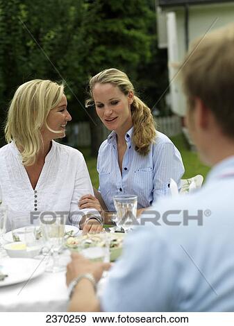 Stock Photo - Two women smiling at garden table . Fotosearch