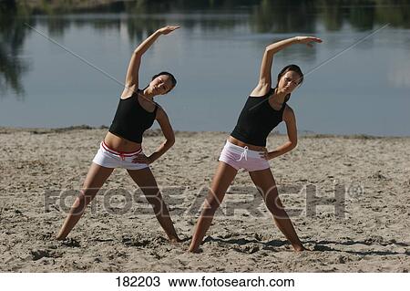 Two young women doing fitness exercises at beach, full shot View Large Photo Image Stock Image - Two young women doing fitness exercises at beach, full shot . Fotosearch