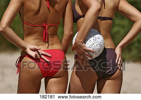 Stock Image - Two young women playing beach volleyball, rear view . Fotosearch