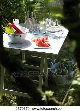 Stock Photo - Watermelon slices with beverages and potted plant on table in garden . Fotosearch