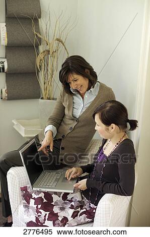 Stock Photography - Woman and her daughter looking at laptop on couch . Fotosearch