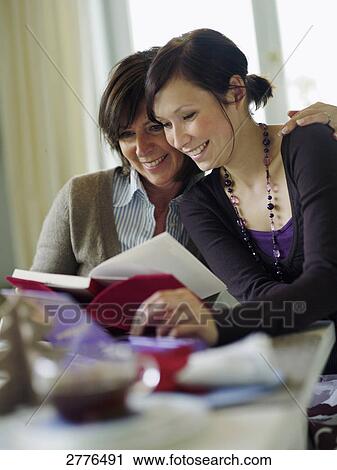 Woman and her daughter reading book at table View Large Photo Image Stock Image - Woman and her daughter reading book at table . Fotosearch