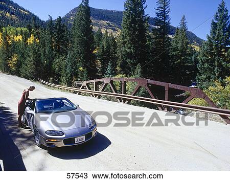 Stock Image - Woman leaning over car on a bridge . Fotosearch