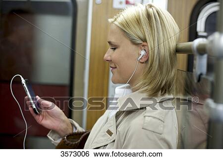 Woman listening to music on cell phone in the subway, profile View Large Photo Image Stock Photograph - Woman listening to music on cell phone in the subway, profile . Fotosearch