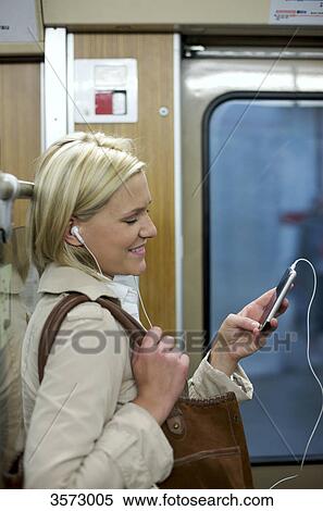 Woman listening to music on cell phone in the subway, profile View Large Photo Image Stock Photography - Woman listening to music on cell phone in the subway, profile . Fotosearch