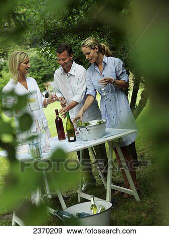 Woman serving drink to her friends at garden party View Large Photo Image Stock Photo - Woman serving drink to her friends at garden party . Fotosearch