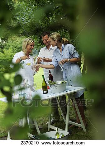 Woman serving water to her friends at garden party View Large Photo Image Stock Image - Woman serving water to her friends at garden party . Fotosearch