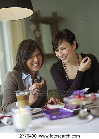 Woman showing cookie to her daughter at breakfast table View Large Photo Image Stock Image - Woman showing cookie to her daughter at breakfast table . Fotosearch