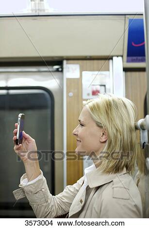 Woman using cell phone in the subway, profile View Large Photo Image Picture - Woman using cell phone in the subway, profile . Fotosearch