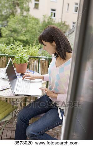 Woman using laptop on balcony View Large Photo Image Stock Image - Woman using laptop on balcony . Fotosearch
