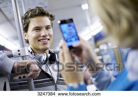 Young man in metro getting photographed with camera phone, slanted view View Large Photo Image Picture - Young man in metro getting photographed with camera phone, slanted view . Fotosearch