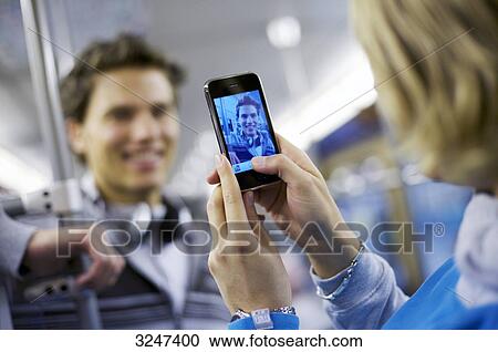 Young man in metro getting photographed with camera phone, slanted view View Large Photo Image Stock Image - Young man in metro getting photographed with camera phone, slanted view . Fotosearch