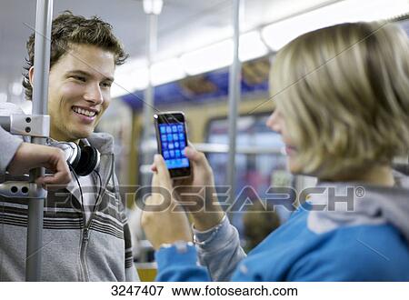 Young man in metro getting photographed with camera phone View Large Photo Image Stock Photo - Young man in metro getting photographed with camera phone . Fotosearch