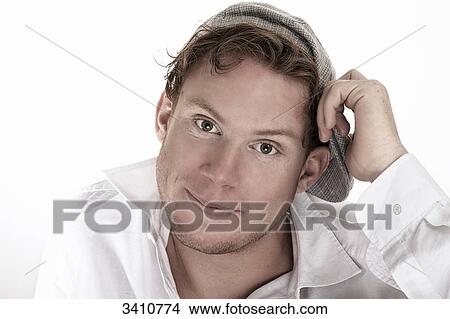 Picture - Young man in white shirt with flat cap smiling at camera, portrait . Fotosearch