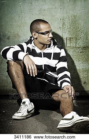 Young man sitting in front of a gate, portrait View Large Photo Image Stock Photograph - Young man sitting in front of a gate, portrait . Fotosearch