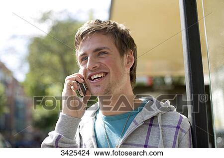 Young man talking on mobile phone, low angle view View Large Photo Image Picture - Young man talking on mobile phone, low angle view . Fotosearch