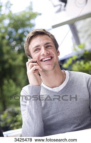 Stock Photo - Young man talking on mobile phone, low angle view . Fotosearch