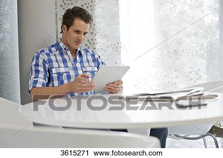 Young man using iPad View Large Photo Image Stock Image - Young man using iPad . Fotosearch