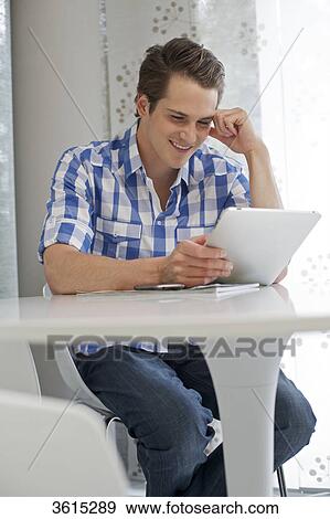Young man using iPad View Large Photo Image Stock Photo - Young man using iPad . Fotosearch