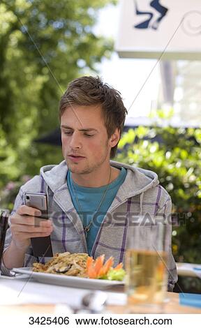Young man using mobile phone, low angle view View Large Photo Image Stock Photograph - Young man using mobile phone, low angle view . Fotosearch
