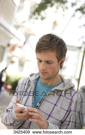 Stock Photo - Young man using mp3-player, low angle view . Fotosearch
