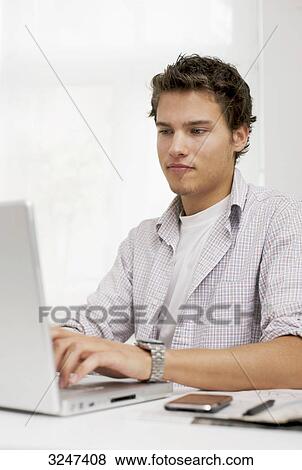 Stock Photo - Young man using notebook, waist up . Fotosearch