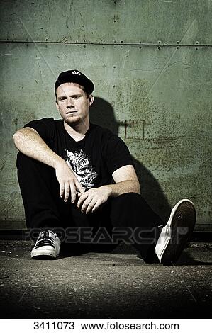 Young man with baseball cap sitting in front of a gate, portrait View Large Photo Image Stock Image - Young man with baseball cap sitting in front of a gate, portrait . Fotosearch