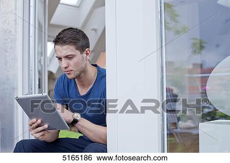 Stock Photograph - Young man with ipad . Fotosearch