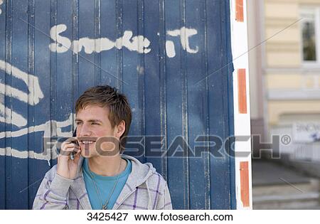 Young man with mobile phone standing in front of a container View Large Photo Image Stock Photo - Young man with mobile phone standing in front of a container . Fotosearch
