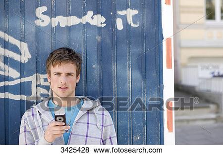 Young man with mobile phone standing in front of a container View Large Photo Image Stock Photo - Young man with mobile phone standing in front of a container . Fotosearch