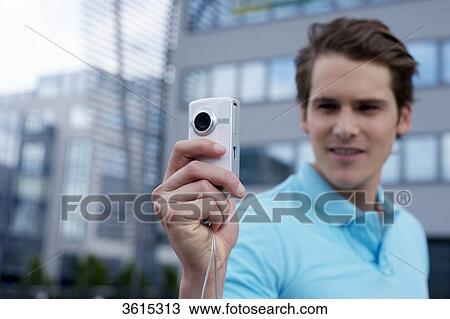 Stock Image - Young man with smartphone in front of office building . Fotosearch
