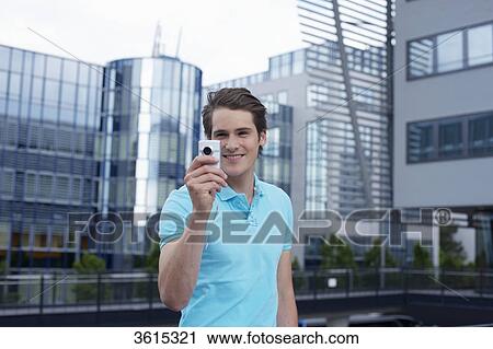 Stock Image - Young man with smartphone in front of office building . Fotosearch