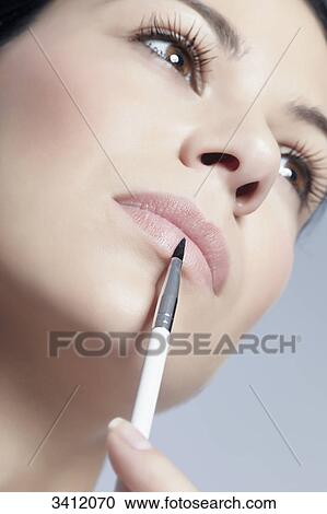 Young woman applying lipgloss View Large Photo Image Stock Image - Young woman applying lipgloss . Fotosearch