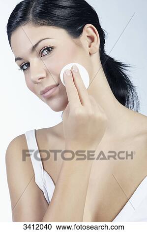 Stock Image - Young woman cleaning her face . Fotosearch