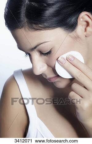 Stock Image - Young woman cleaning her face . Fotosearch