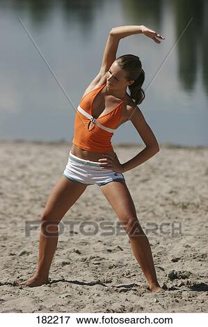 Stock Photo - Young woman doing yoga on lake beach . Fotosearch