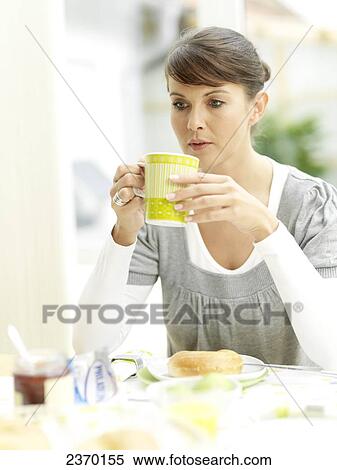 Stock Photography - Young woman drinking coffee and thinking . Fotosearch